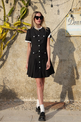 a lady in a black pleated dress with ruffle collar and trim